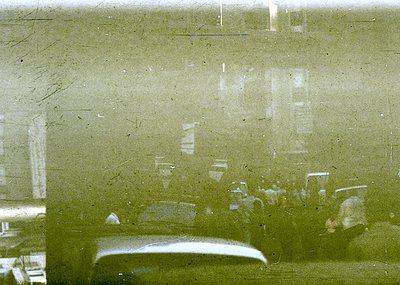 Vintage close-up of a fogged or scratched glass surface reflecting indistinct indoor objects—likely a mirror or window. Refle...