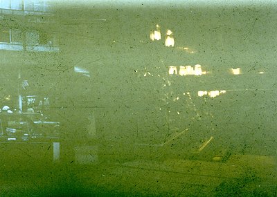 Vintage close-up of a foggy, rain-streaked window reflecting blurred city lights and indistinct architecture. Warm streetligh...