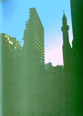 Mid-century modernist high-rise framed by Islamic minaret, likely –70s urban architecture. Concrete Brutalist facade contrast...
