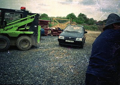 Vintage construction site with a green **Lutec 750** loader (Krupina brand) and a mid-1980s **Volkswagen Golf** parked on gra...