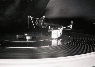 Vintage vinyl record on a turntable with a close-up of the tonearm and stylus in lowered position. The design highlights mid-...