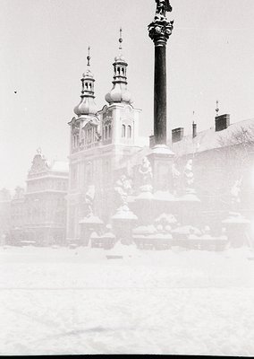 Historic Baroque-style cathedral with twin domed towers partially obscured by mist/snow. Ornate façade and decorative column ...