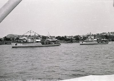 Mid-20th century naval vessels in port, likely Eastern Bloc-era. Two ships with "DRN" markings and a third with "PR 11" in ca...