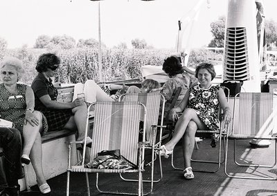Black-and-white photo of four women relaxing on vintage deck chairs on a sun deck, likely mid-20th century. Two women in flor...
