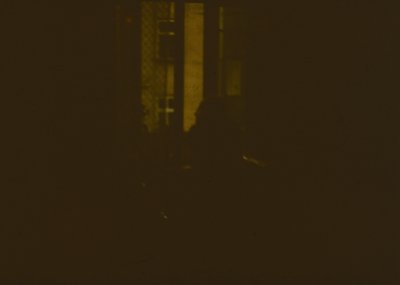 Low-light urban scene with minimal detail—blurred vertical structure (likely a building or pole) and faint horizontal lines s...