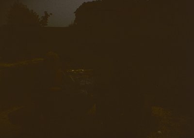 Low-contrast black-and-white nighttime shot of a **mountainous landscape** with faint outlines of rocky ridges and a distant ...