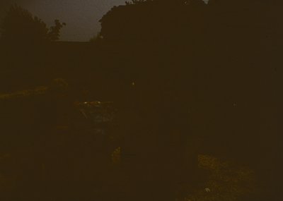 Low-light urban scene with faintly visible streetlights and indistinct architecture. Ambient glow suggests nighttime cityscap...