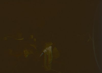 Vague low-light shot of a person holding a cigarette in an indoor setting, likely a bar or lounge. Blurred details obscure fa...