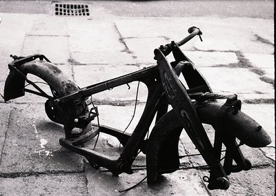 Vintage motorcycle frame with sidecar, likely mid-20th century. Rust and wear indicate prolonged outdoor exposure. Frame feat...