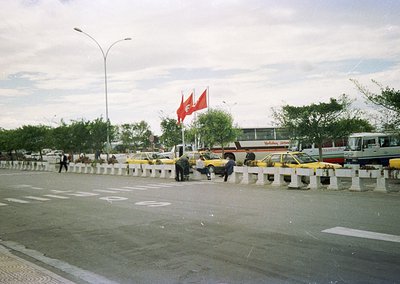Urban scene featuring a busy roundabout with yellow taxis, a prominent Turkish flag, and Soviet-era architecture in backgroun...