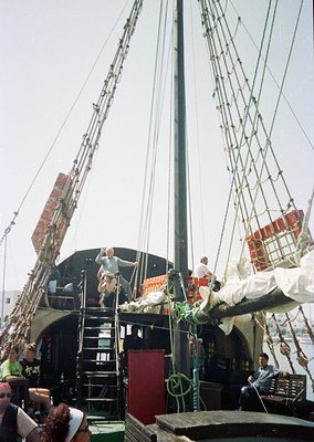 Reproduction of a 17th–18th century sailing ship deck, likely for maritime education or film. Crew in period attire climbs ri...