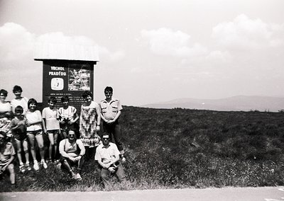 Black-and-white group photo at a mountain summit signpost reading "Vrchol Pradědu" (Praděd Peak, Czech Republic), 1960s–70s. ...