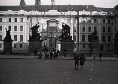 Neoclassical gatehouse with sculpted lions flanking an ornate archway, set against symmetrical palace wings. Mid-20th century...