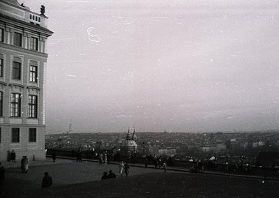 Vintage black-and-white coastal cityscape featuring a grand, multi-story building with ornate architectural details. Prominen...