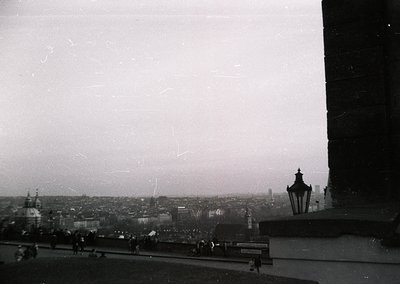 Vintage black-and-white cityscape shot from an elevated viewpoint, likely a balcony or rooftop. Distinctive spire and ornate ...