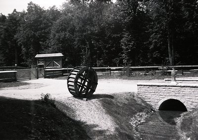 Historic waterwheel in a rural setting, likely part of an old mill or irrigation system. The brick-lined channel and wooden g...