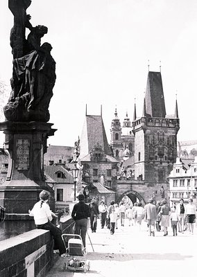 Black-and-white shot of Prague’s Charles Bridge (14th century) featuring Gothic-style statues and medieval architecture. Crow...