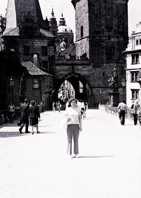 Mid-20th century black-and-white shot of Prague’s Charles Bridge, featuring Gothic arches, domed towers, and historic lantern...
