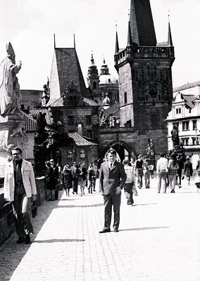 Black-and-white street scene at Prague’s Charles Bridge () during the 1960s (). Gothic towers, statues, and historic stone ar...
