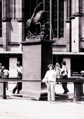 Neoclassical equestrian statue atop a stone pedestal in an urban plaza, surrounded by classical architecture. A woman in 1970...