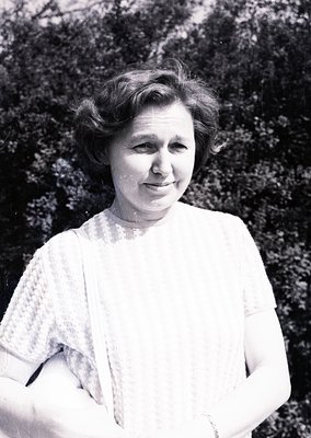 Mid-century portrait of a woman in a light, textured blouse with rolled sleeves, likely 1940s–1950s. Soft focus and natural o...