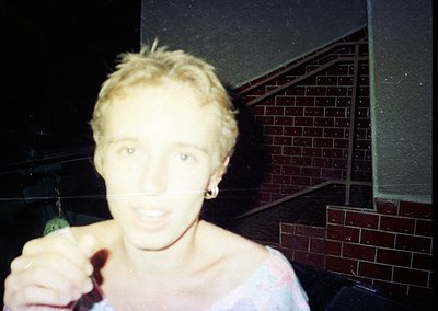 Vintage candid shot of a person holding a green bottle, likely beer, in a dimly lit indoor setting with brick-patterned wall....