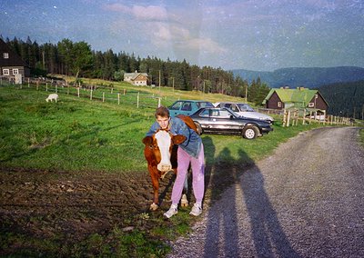 Vintage rural scene with two individuals hugging a brown horse beside a gravel road. Classic 1970s-era station wagons parked ...