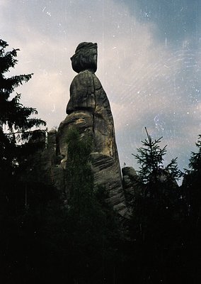 Carved sandstone rock formation resembling a seated human figure in a forested landscape. Likely part of the **Rügnitz Rocks ...