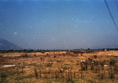 Vintage aerial view of dry, rural terrain with sparse vegetation and scattered structures. Likely agricultural or undeveloped...