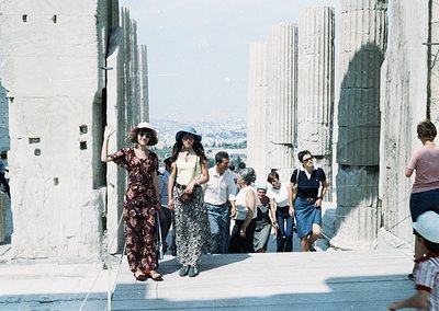 Vintage 1960s photograph of a group walking along the Parthenon ruins in Athens, Greece. Architectural columns and ancient st...