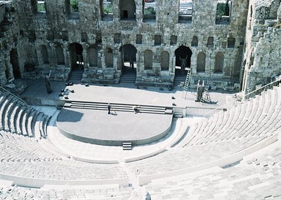 Ancient Roman amphitheater with tiered stone seating and central stage area, likely from the 1st–2nd century CE. Stone arches...