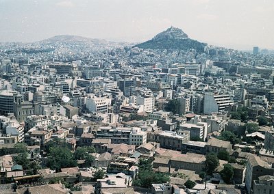 Aerial view of Athens, Greece, showcasing dense urban sprawl with mid-20th-century architecture. The Acropolis dominates the ...