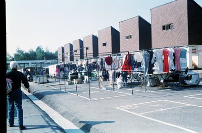 Communal rooftop laundry area with concrete slabs, metal racks, and drying clothes in a Soviet-era apartment block. A man in ...