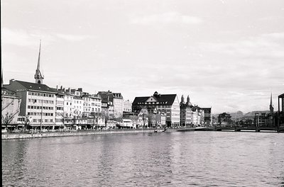 Black-and-white waterfront view of Zurich’s Limmat River, showcasing early-to-mid 20th-century European architecture. Promine...