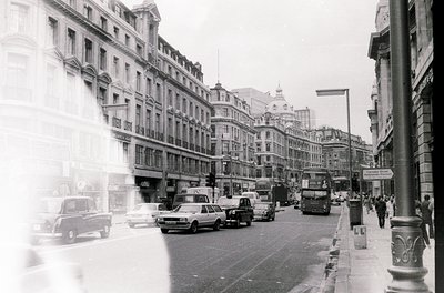 Classic mid-20th century urban street scene featuring Edwardian-era architecture. Multi-story brick buildings with ornate fac...