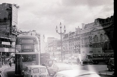 Classic mid-20th century London street scene with iconic double-decker bus (route 15) and vintage cars. Edwardian-era buildin...