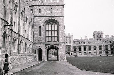 Gothic-style stone courtyard entrance with pointed arches, tall lancet windows, and buttresses. Mid-20th century institutiona...