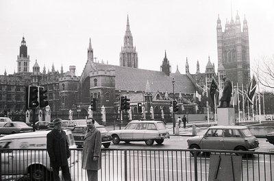 Black-and-white street scene at Westminster, London, featuring iconic Gothic architecture of the Palace of Westminster and Bi...