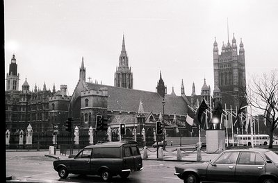 Black-and-white shot of **Westminster Abbey** and **Houses of Parliament** (Big Ben) in London, UK, c. 1960s–1970s. Gothic ar...
