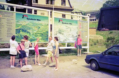 Vintage 1970s alpine tourist scene at **Spindlerův Mýtň** (Czech Republic). Five hikers in retro outdoor wear examine detaile...