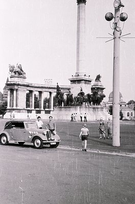1950s-era monument with equestrian statues and classical columns in Budapest, Hungary. A vintage car with passengers poses ne...