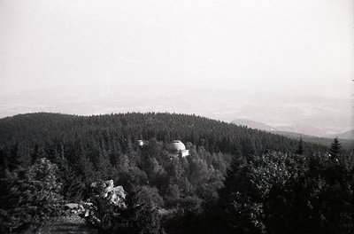 Vintage black-and-white aerial view of a domed structure nestled in a forested hillside, likely a Soviet-era observation towe...