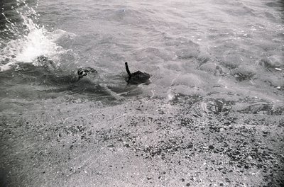 Black-and-white shot of a vintage military tank partially submerged in churning water, likely during amphibious training or t...