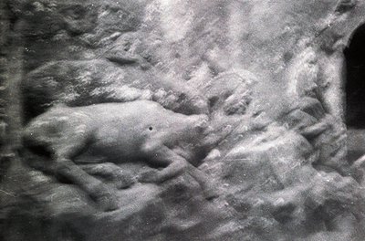 Close-up of a **stone relief sculpture** depicting a reclining figure, likely a historical or mythological subject. The intri...