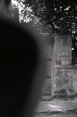 Vintage black-and-white photo of a dimly lit alleyway with a sign reading "ПОТО ПОТО" (Bulgarian for "pot pot," possibly a gr...