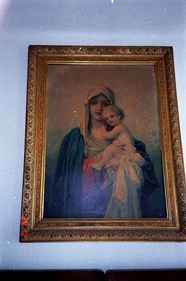 Vintage religious portrait depicting the Virgin Mary cradling Christ Child, framed in ornate gold leaf. Soft brushstrokes and...