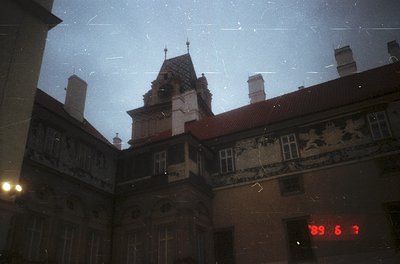Vintage black-and-white photo of a European courtyard with ornate, multi-story building featuring Gothic Revival architecture...