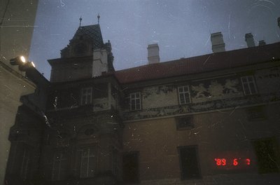 Reflection of a historic European building facade with ornate stone carvings—likely 19th-century—showing decorative motifs an...