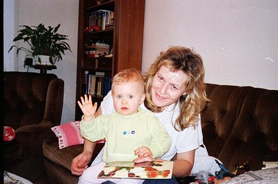 Vintage indoor portrait of a woman and toddler in a cozy living room, likely late 1990s–early 2000s. Woman in a white top hol...