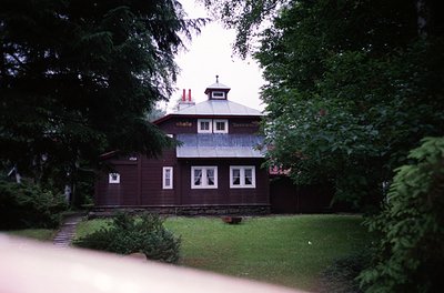 Two-story wooden building with a gabled roof, featuring a small tower-like extension on the upper floor. The signage "Chalet"...